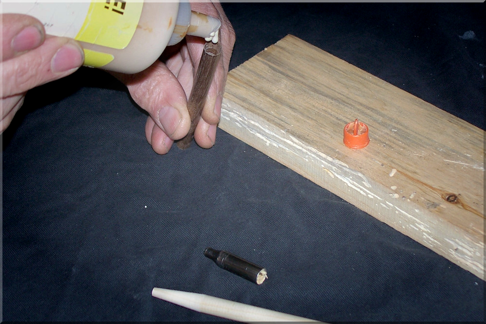 Photo. A man applies glue to a wooden Reparrow footing to fix a nearby wood arrow.