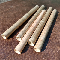 Five hollow maple dowels (Reparrows) lying flat in a line on a leather surface.